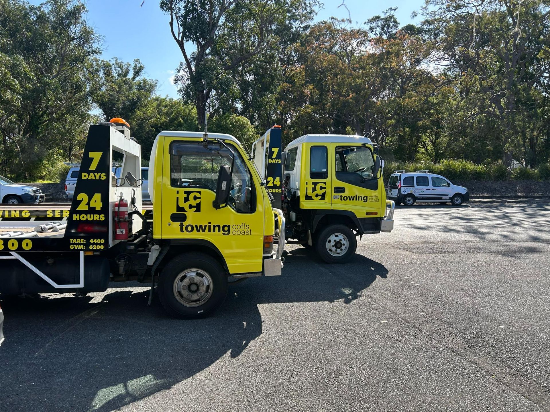 two Yellow Til Towing truck parked next to each other