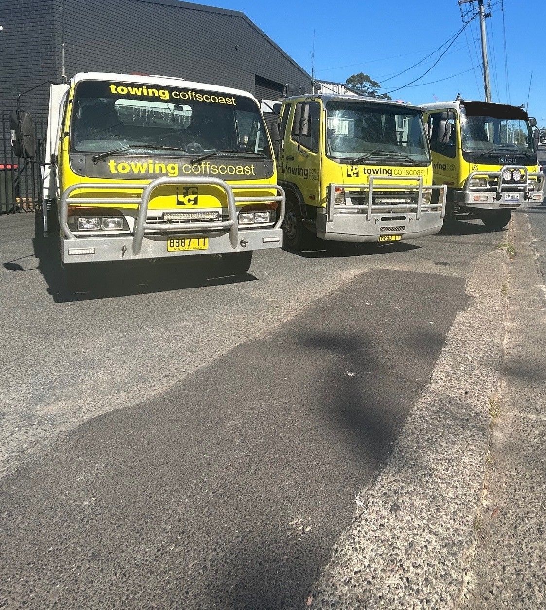 two Yellow Til Towing truck parked next to each other