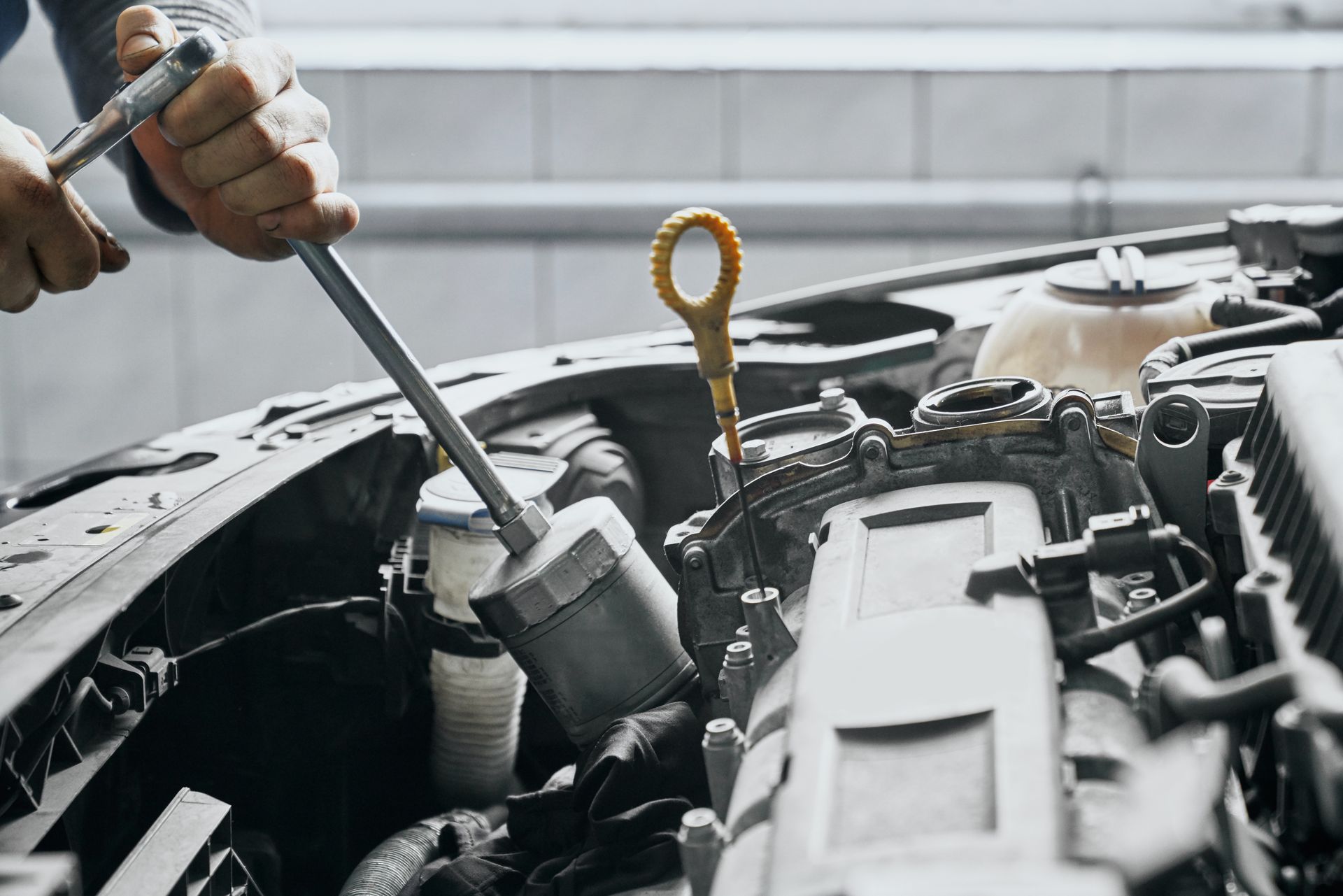 Three men work on a race car engine, under a tent and near a trailer with 