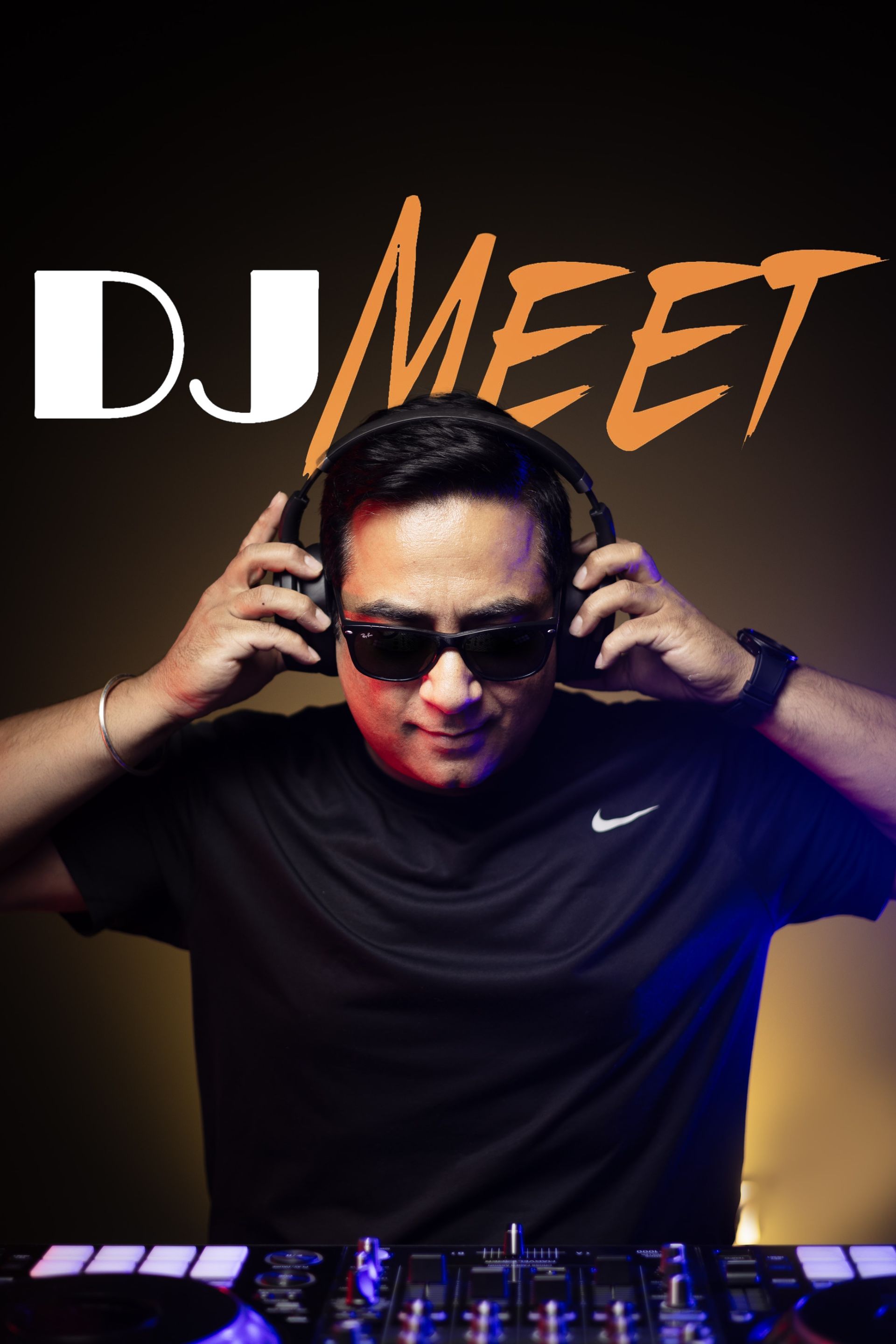DJ Meet, man wearing sunglasses and headphones, adjusting them while standing in front of DJ equipment.