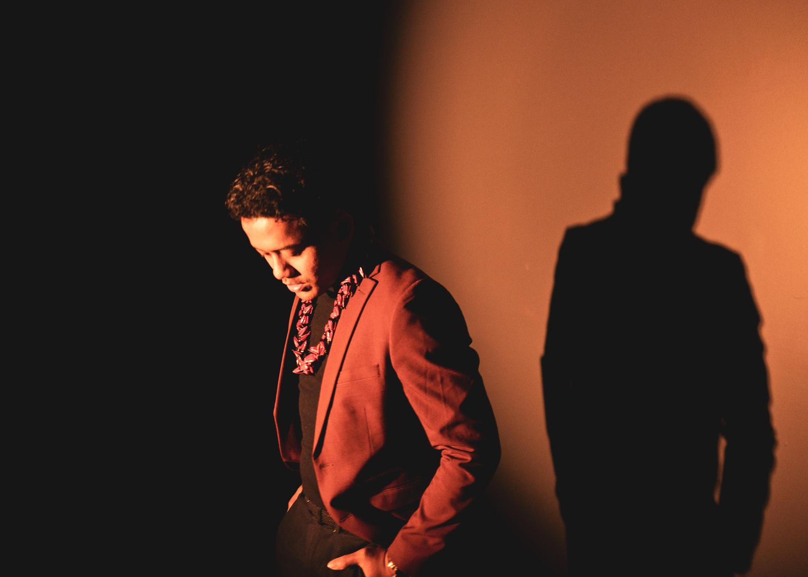 Person in a red jacket standing in warm light with a large shadow on the wall
