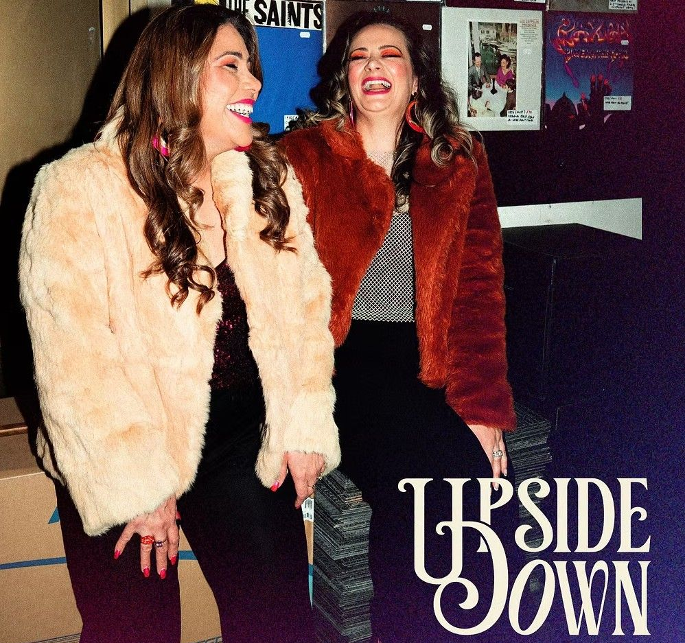Two women laughing together, wearing faux fur jackets.