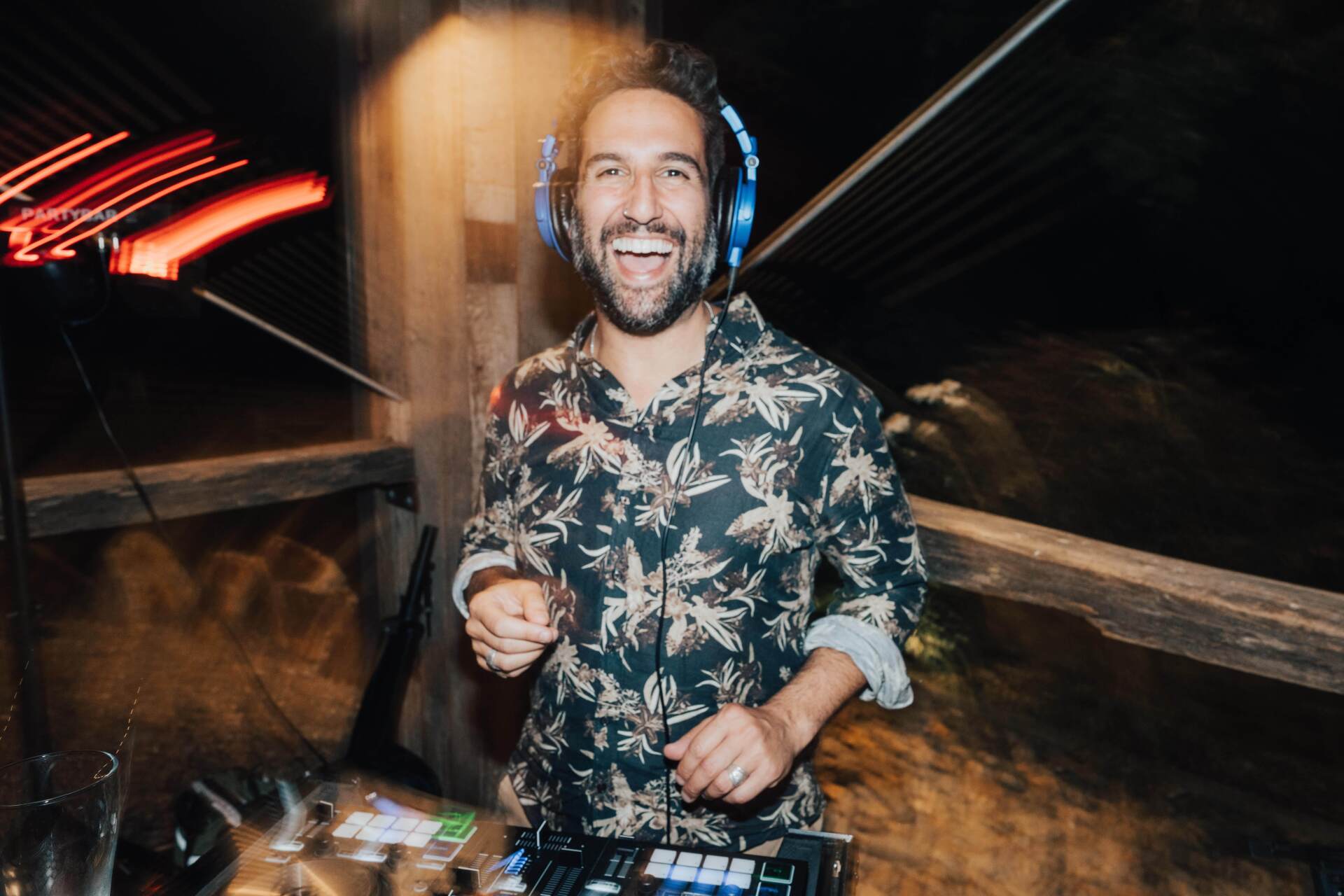 A man wearing headphones is playing music at a party.