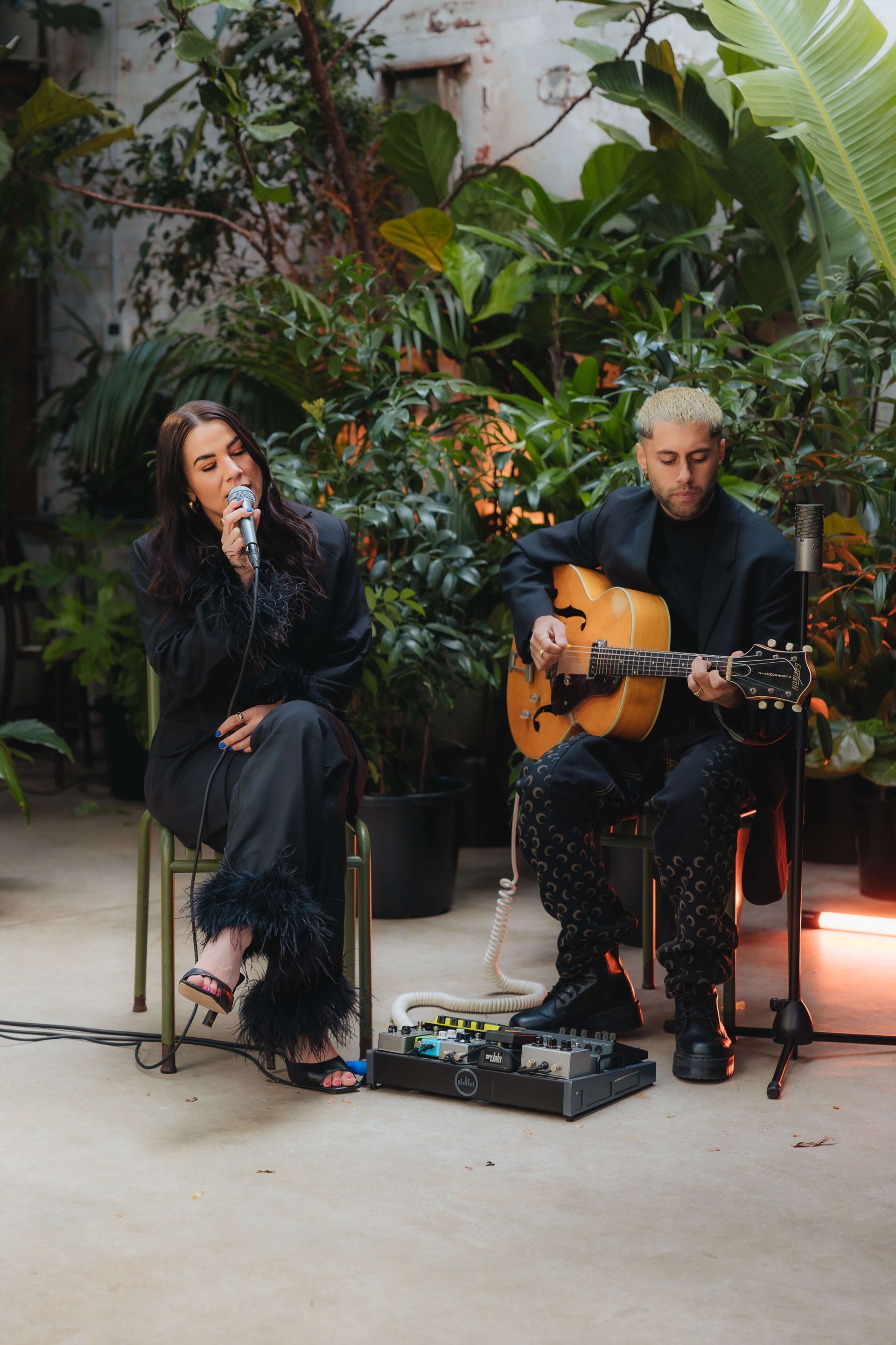 A man is playing a guitar and a woman is singing into a microphone.