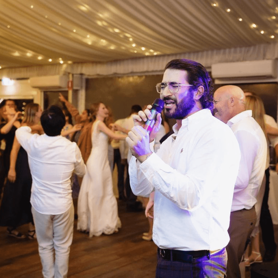 A man is singing into a microphone at a wedding reception.