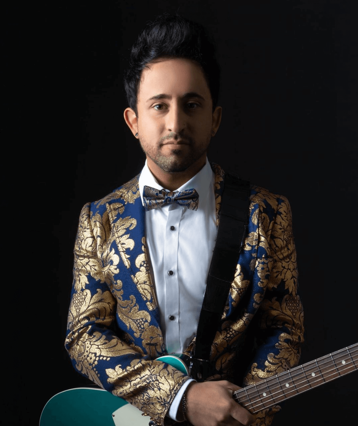 A man in a suit and bow tie is holding a guitar.