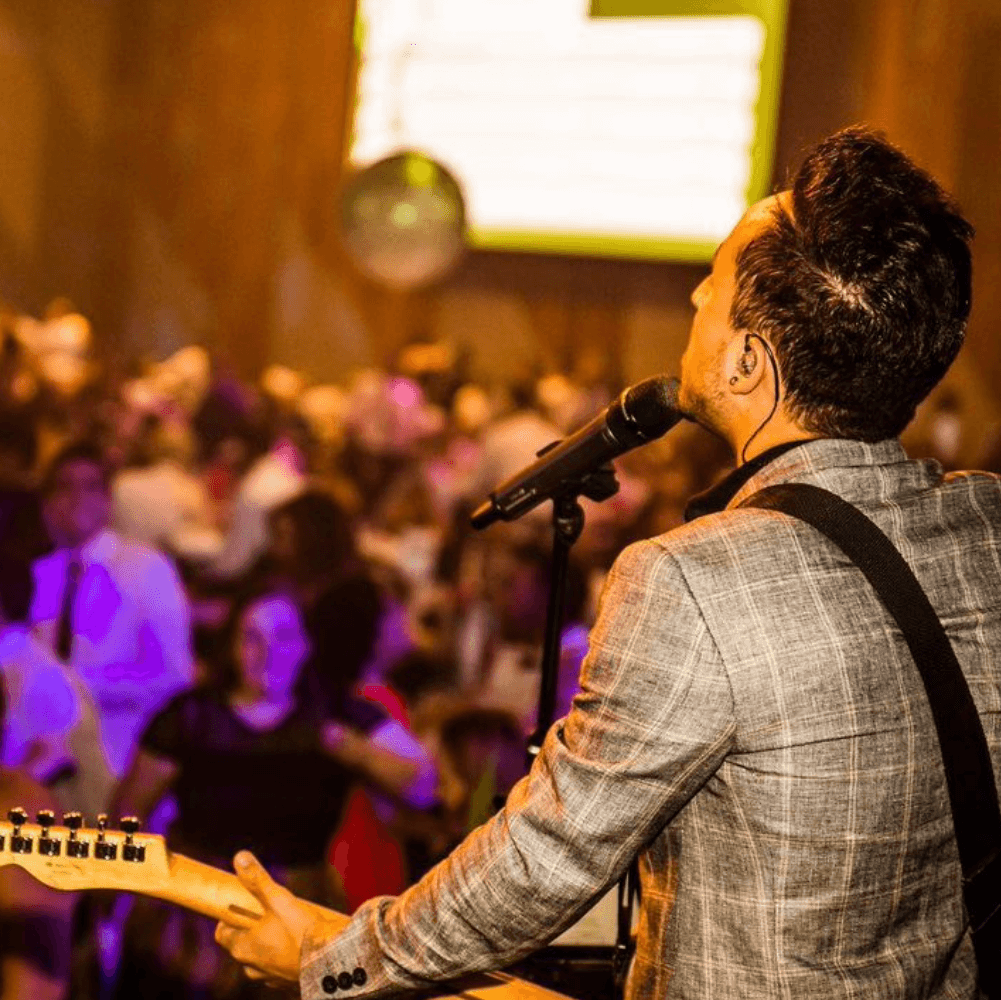 A man is singing into a microphone while playing a guitar