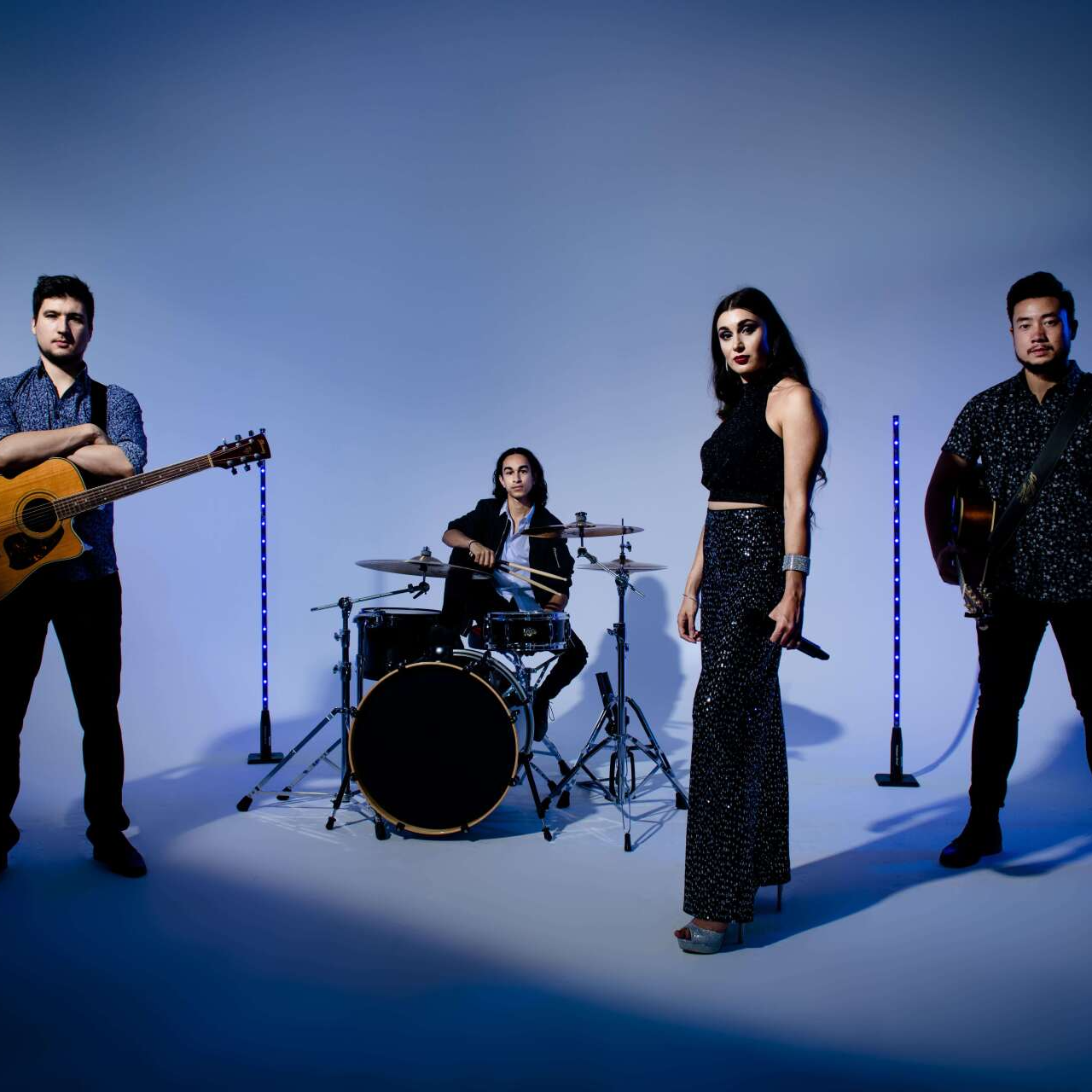Band of four against a blue backdrop: singer, drummer, two guitarists.