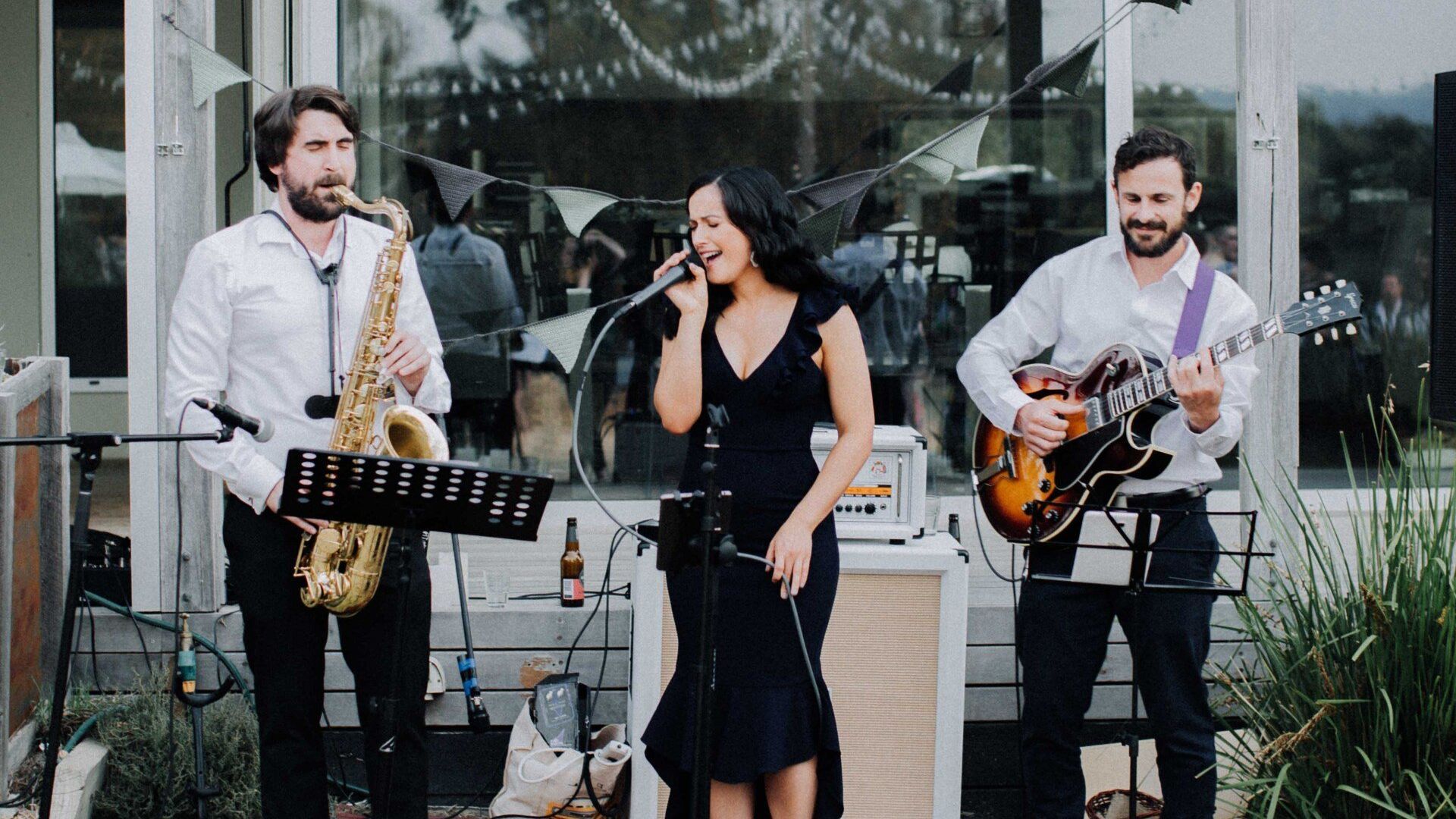 A man is playing a saxophone and a woman is singing into a microphone.