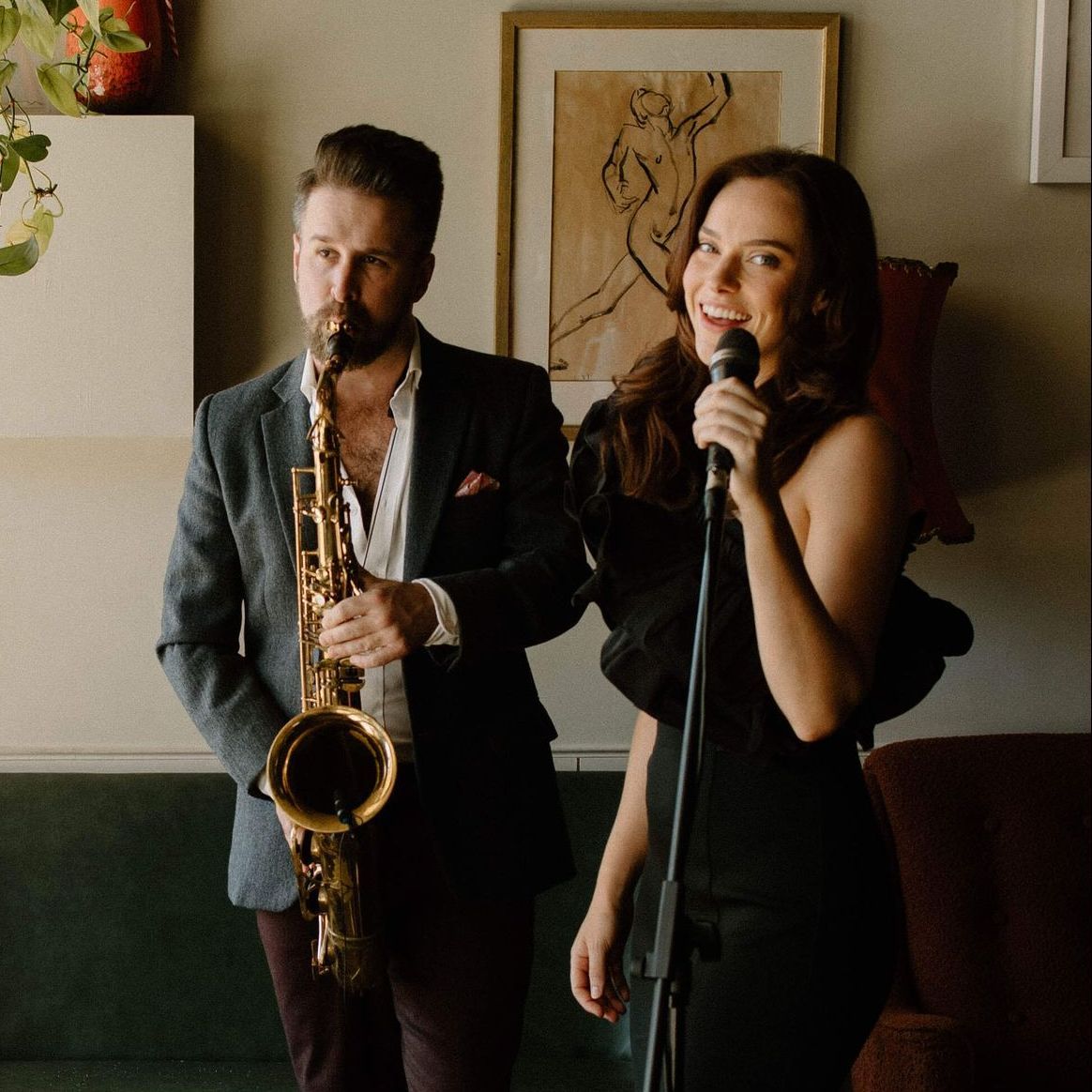 Man with saxophone and woman with microphone, performing music indoors.