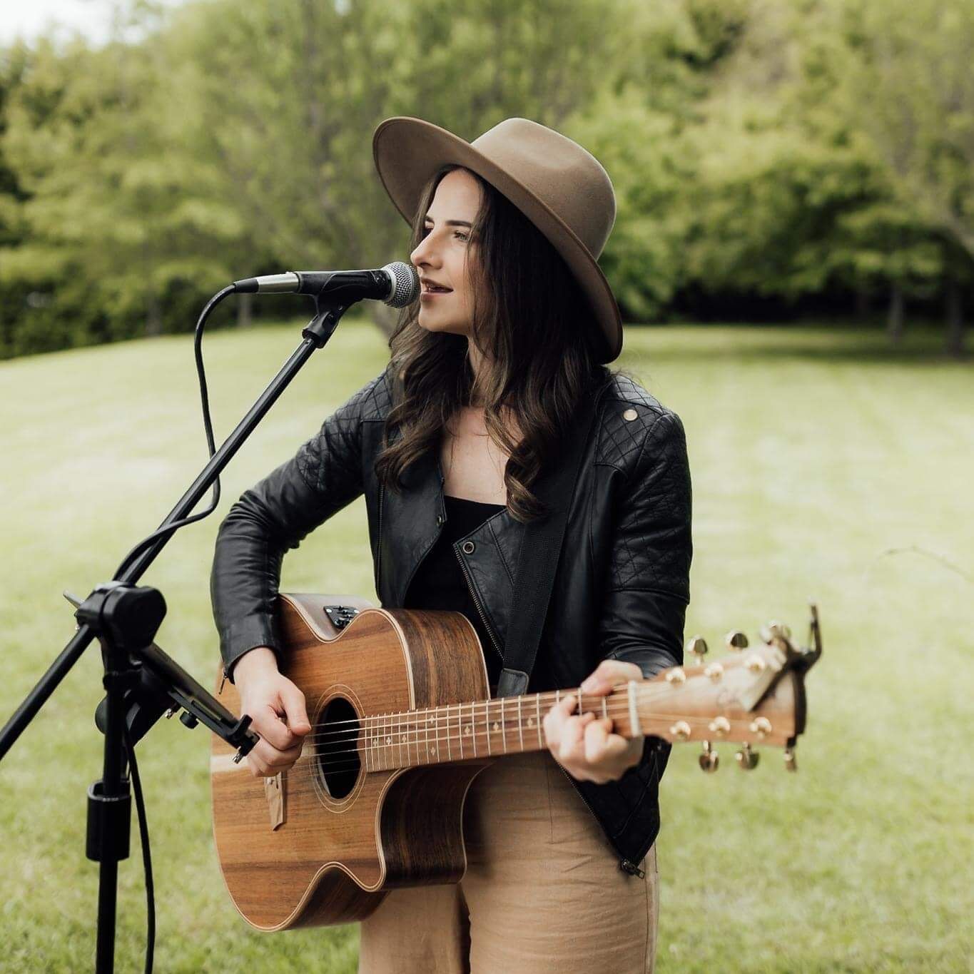 A woman singing into a microphone while holding a guitar