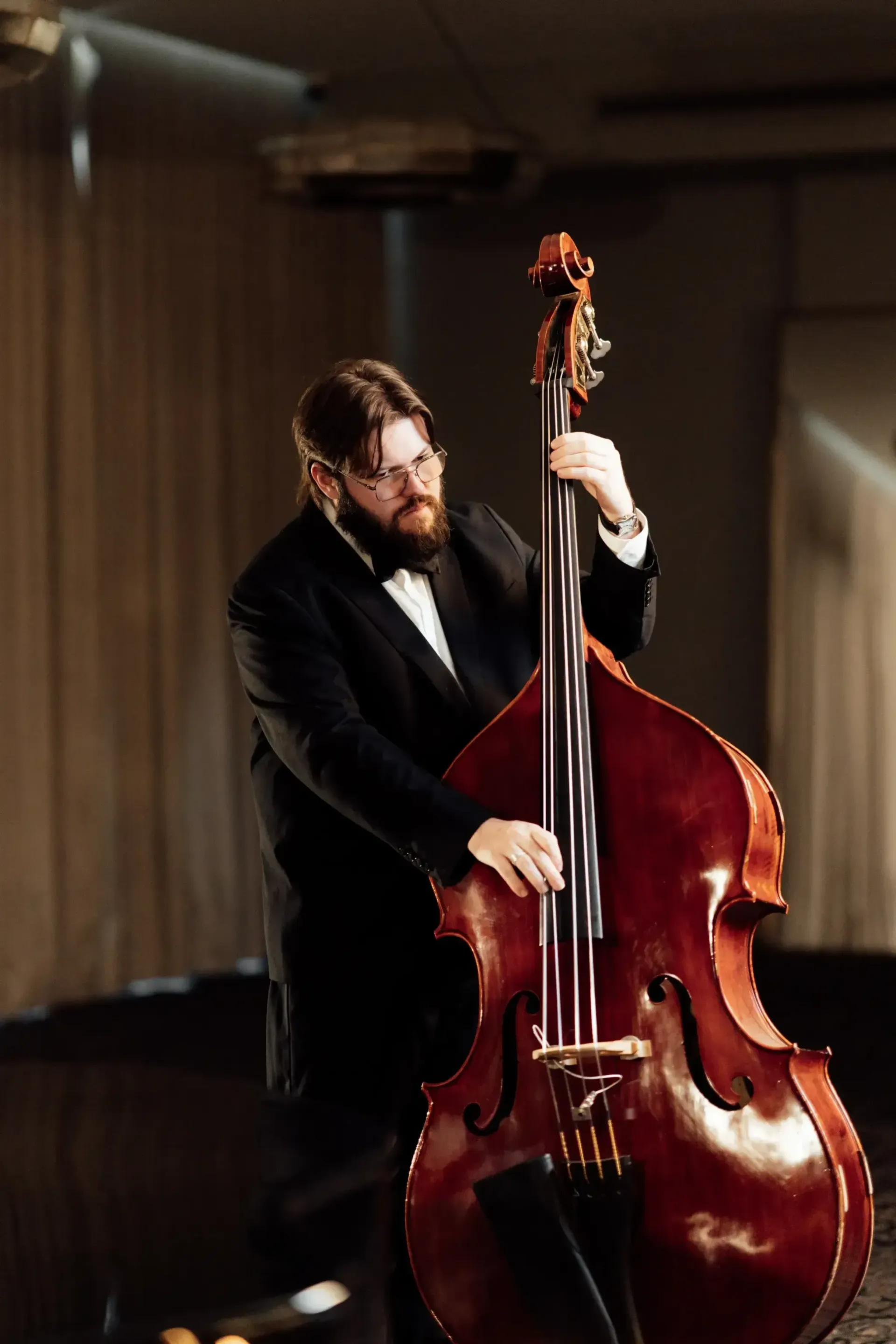 Bearded musician playing an upright bass on a dimly lit stage