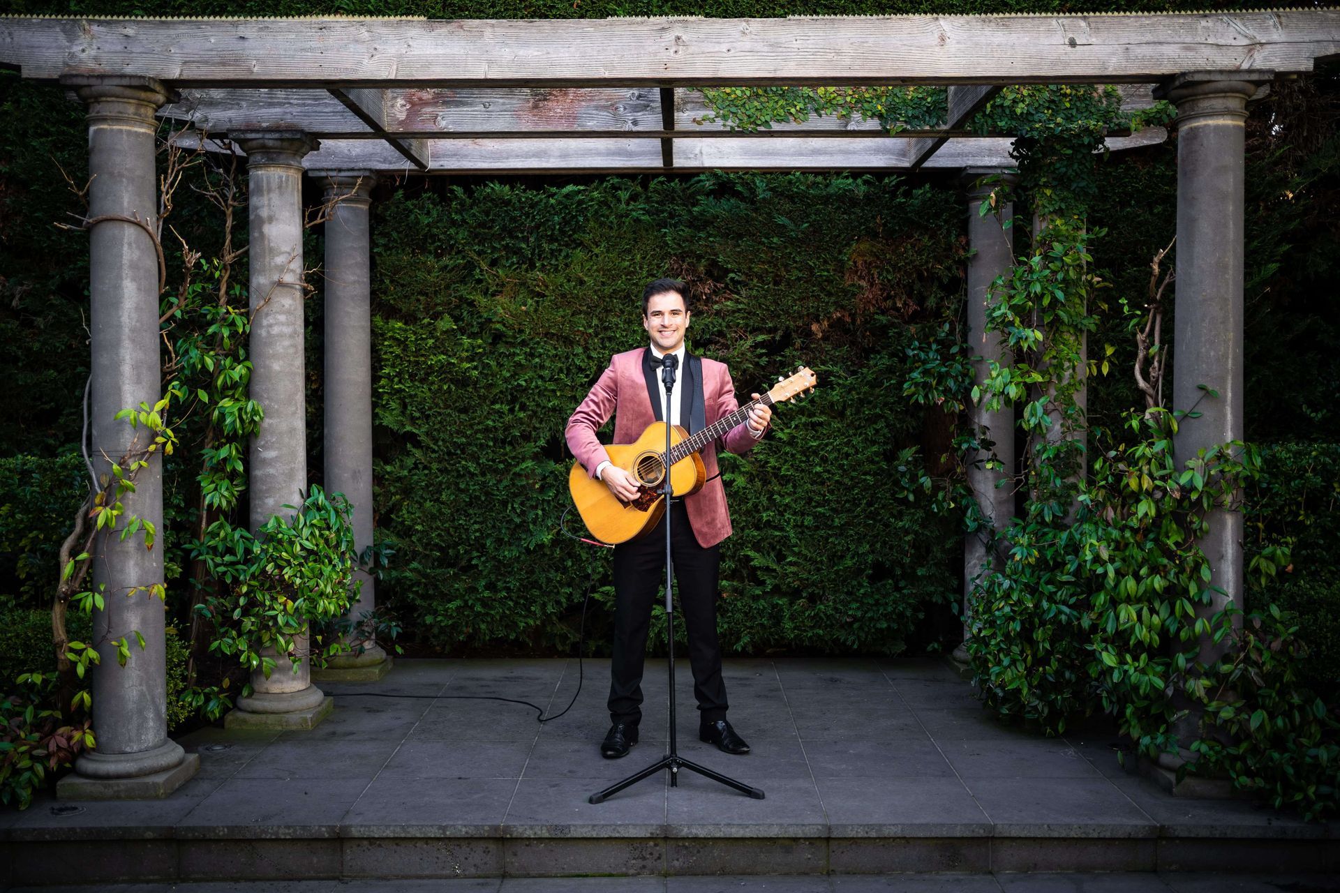 A man in a suit is playing a guitar in front of a microphone.
