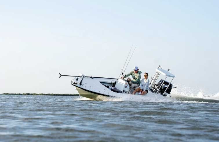 Small white fishing boat tilted in choppy water with several people aboard near the horizon