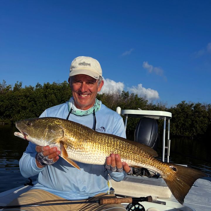 Man holding a large fish on a boat under a clear blue sky