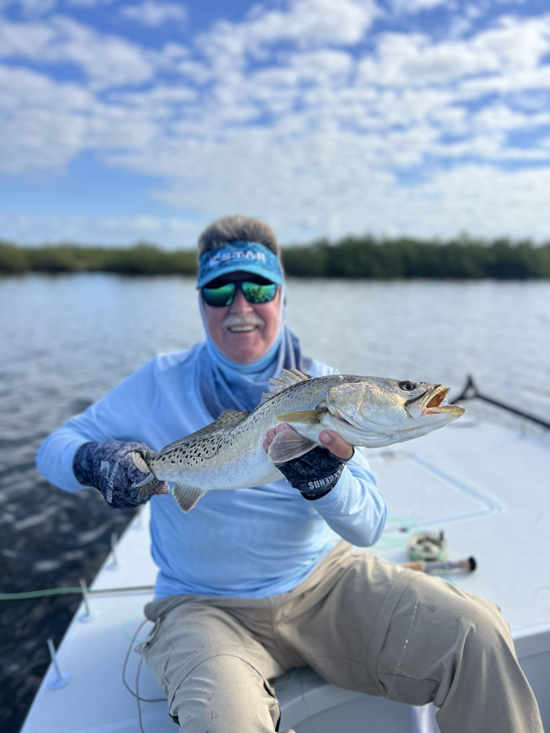 Person on a boat holding a large fish on a sunny lake