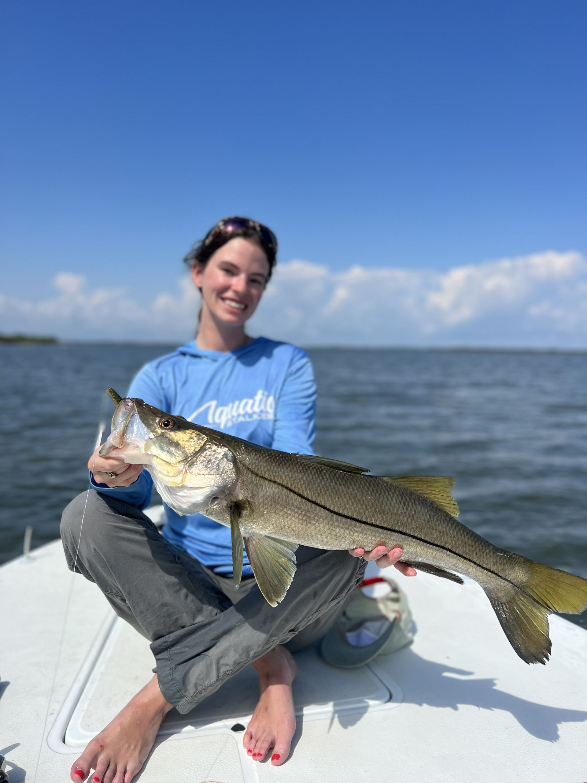 Person on a boat holding a large fish on a sunny day at sea.