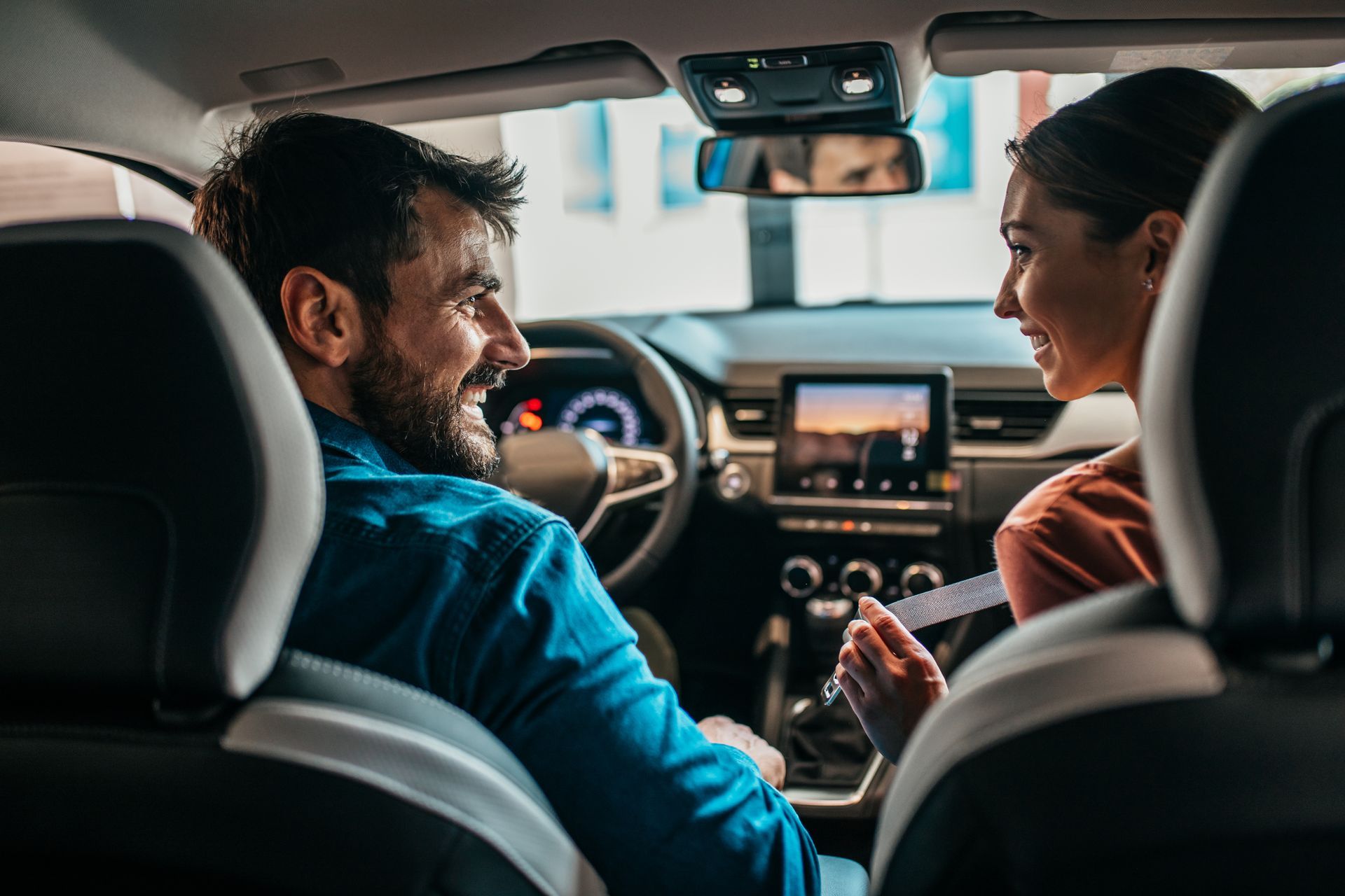 a man and a woman are looking at each other in the back seat of a car