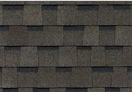 Dark gray asphalt roof shingles in a close-up pattern.