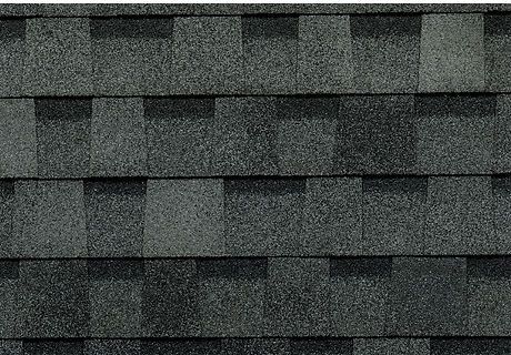 Close-up of dark gray asphalt roof shingles with staggered rows and textured grain.