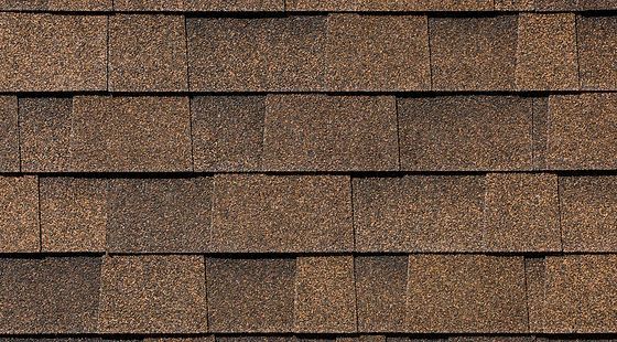 A close up of a roof with brown shingles.