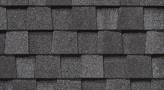 Close-up of dark gray asphalt roof shingles in a staggered pattern.