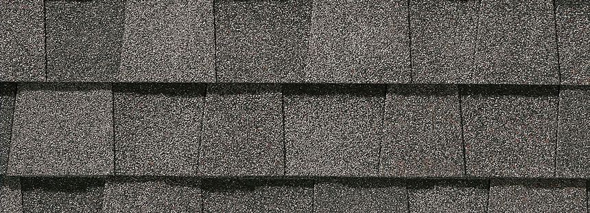 Gray asphalt shingles on a roof, arranged in overlapping rows with horizontal dark seams.