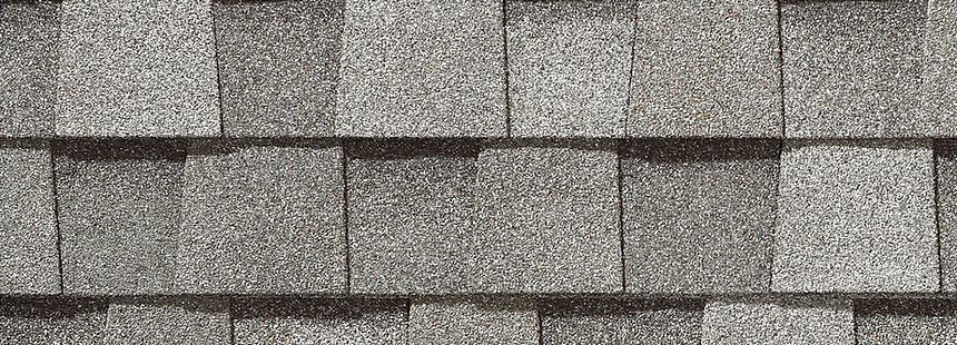 Close-up of gray asphalt shingles on a roof, showing layered rows and texture.