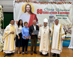 Group posing at a church event beside a banner reading “80 years of faith & service”