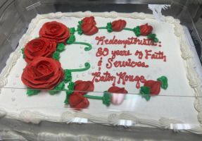 Rectangular white cake with red rose frosting and red message celebrating 20 years of faith and service