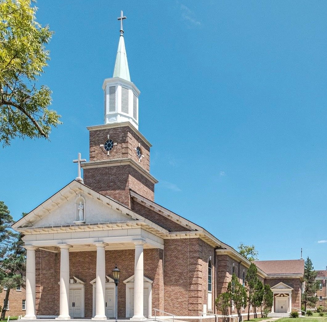 Brick church with white columns and steeple against a bright blue sky