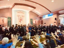 Large group of people in a church, many raising hands during a worship service