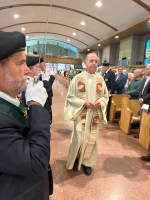 Clergy processing through a church aisle during a formal service, with congregants seated on both sides.