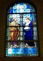 Stained-glass window of two robed figures facing each other in a church setting