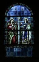 Stained-glass window with two robed figures standing beneath a blue arched design