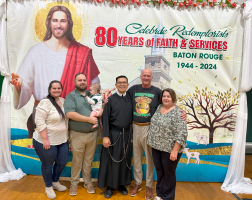 Group posing at a church anniversary event in front of a “80 years of faith & services” banner.