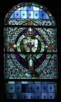 Stained glass church window with blue, green, and purple geometric and circular designs