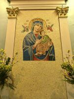 Mosaic of the Virgin Mary holding baby Jesus on a gold altar backdrop with flowers on either side