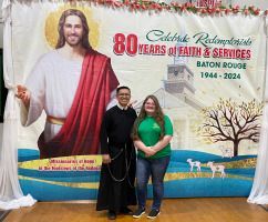 Two people posing before a colorful 80 Years of Faith & Services Baton Rouge 1944–2024 backdrop