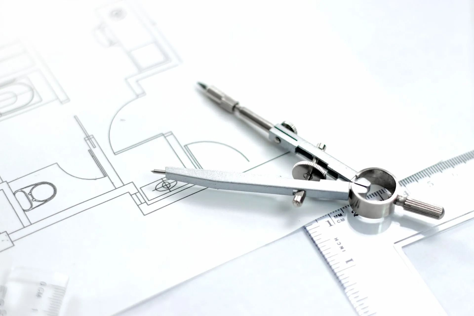 Strumenti da disegno su una planimetria architettonica, tra cui compasso e matita.