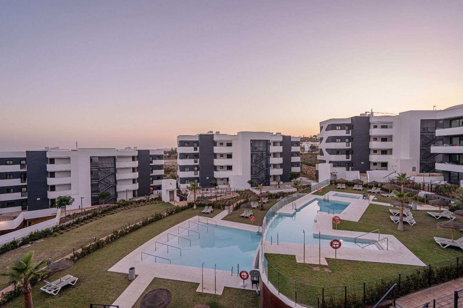 Modern apartment complex with swimming pools and landscaped courtyard at dusk