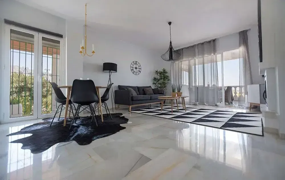 Modern open-plan living room with black-and-white decor, large windows, and glossy marble floors