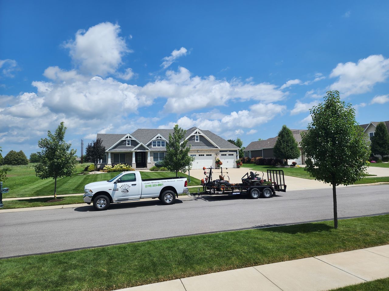 White pickup towing a trailer in front of a suburban house on a sunny day