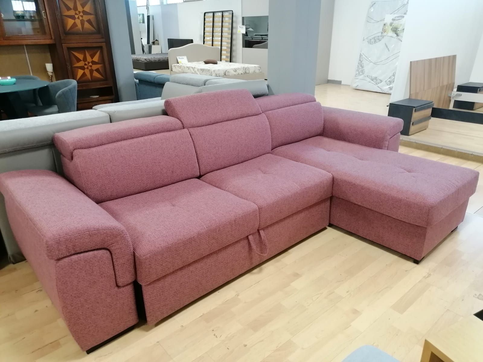 Un divano componibile rosa è appoggiato su un pavimento in legno