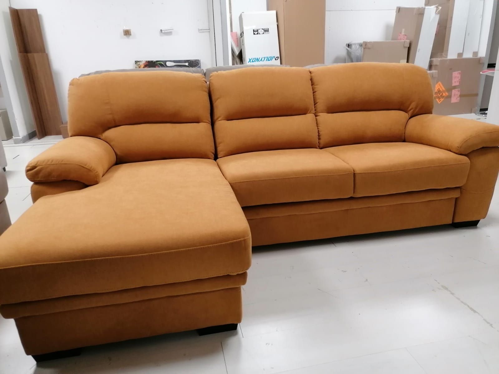 Un divano componibile marrone è appoggiato sul pavimento bianco in una stanza.