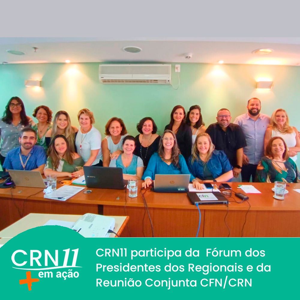 Grupo reunido em sala de reunião, sorrindo, com laptops, banners do CRN11 e parede verde ao fundo.