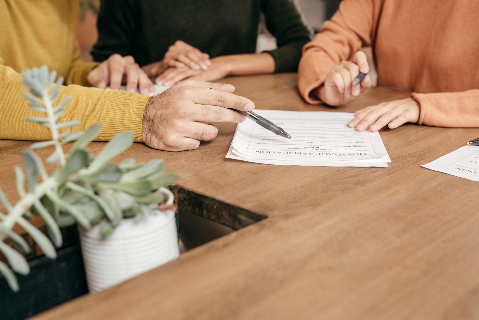 People reviewing document together at a wooden table. One person points with a pen.