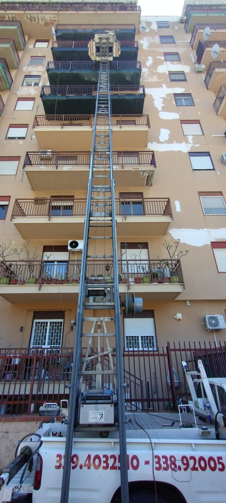 Un edificio alto con un elevatore a scale installato per spostare gli oggetti dai balconi.