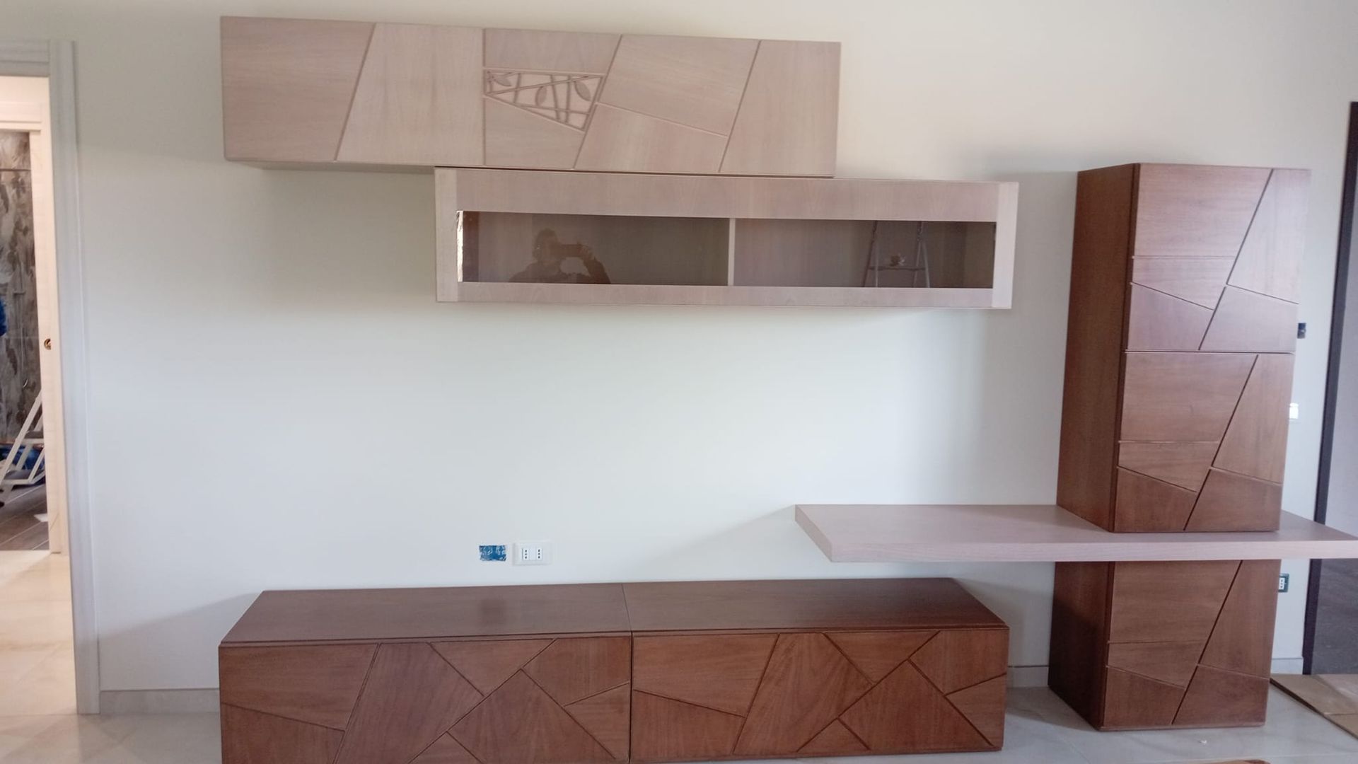 Mobile porta TV moderno da parete in legno con design geometrico. Include ripiani, armadietti e scrivania.