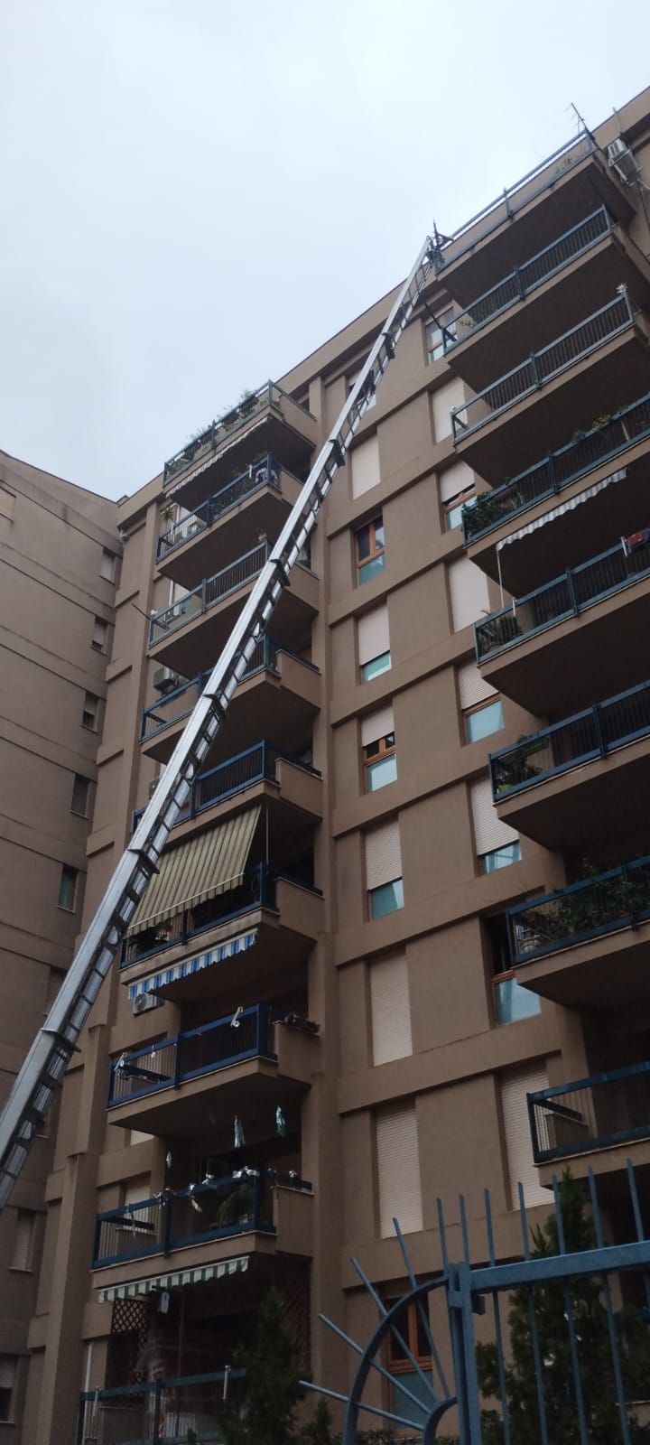 Un edificio con un ascensore esteso, utilizzato per il trasloco. L'edificio è marrone, con balconi e finestre.